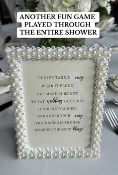 a white table topped with a glass frame filled with pearls and text that reads, another fun game played through the entire shower