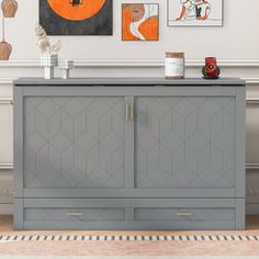 a grey cabinet with two doors and three pictures on the wall