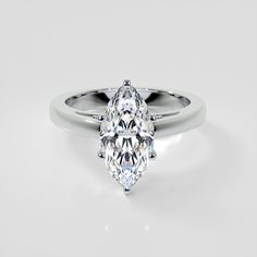 a white gold ring with a pear shaped diamond in the center, on a plain surface