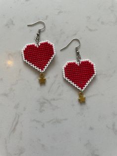 red and white beaded heart shaped earrings with star charms on marble countertop, closeup