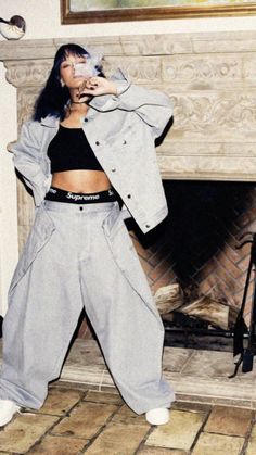 a woman standing in front of a fire place wearing grey sweatpants and a jacket