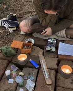 a person sitting on the ground next to some candles and other items that have been placed around them