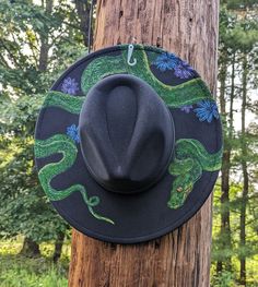 This truly one of a kind piece is perfect to add a spooky flare to your festival outfit or hang as a unique goth themed wall decoration. It's burned entirely by hand using a pyrography tool with an original and freehanded design (never using a stencil or laser machine.) I used a woodburner to engrave the outline and scales of a green tree python slithering through purple and blue wildflowers. Then, I intricately hand painted the details and color with vivid acrylic paint. The burned and painted Snake Cowboy, Green Tree Python, Tree Python, Gothic Birthday, Burned Hats, Hat Burning, Blue Wildflowers, Gifts For Best Friend, Witchy Gifts