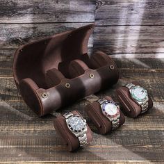 an open leather case with four watches inside on a wooden table next to other watch accessories