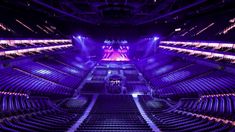 an empty auditorium filled with lots of purple seats and lights on the ceiling, all lit up