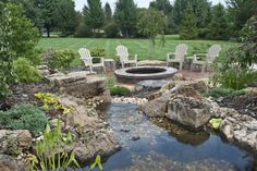 there is a fire pit surrounded by chairs and rocks in the middle of a garden