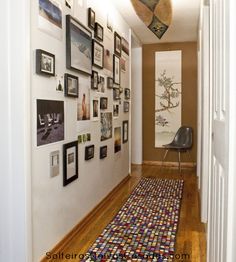 a hallway with pictures on the wall and a rug