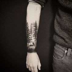 a man with a forest tattoo on his arm