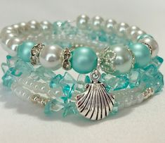 This pretty wrap bracelet features a variety of glass beads in aqua, white and silver. It's accented with a silver tone shell charm making it a great accessory for any occasion! It's also made with memory wire that will give slightly so there's no need for a clasp. Memory Wire Bracelets Ideas, Beading Tips, Handmade Bracelets Tutorial, Beaded Braclets, Memory Wire Wrap Bracelets, Beachy Jewelry, Beach Bracelet, Stack Bracelet, Jewerly Making