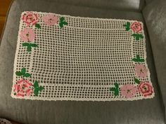 a piece of cloth with pink flowers on it sitting on a gray couch next to a pillow