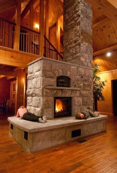 two people laying on the floor in front of an open fire place with wood floors