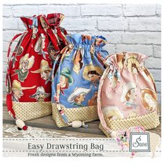 three drawstring bags sitting on top of a wooden table next to a brick wall