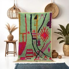 a green rug with pink and yellow designs on it next to a potted plant