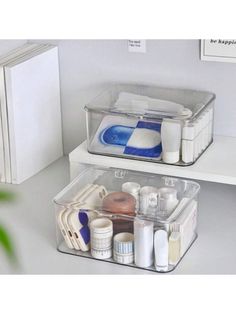 two clear storage containers filled with different items on top of a white counter next to a plant