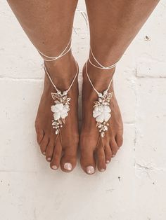 a woman's feet wearing barefoot sandals with flowers and leaves on the anklets