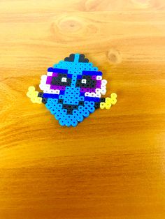 a blue and purple pixel head on a wooden surface