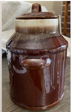 a close up of a brown jar with a white brush in it on a wooden table