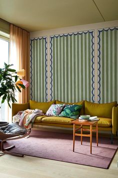 a living room filled with furniture next to a window covered in green and pink curtains