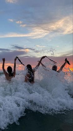 three people in the water with their arms up