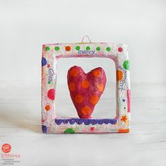 a pink heart in a frame on a white table