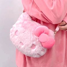 a woman in pink is holding a hello kitty purse