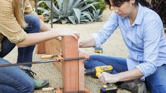 two women are working on a fence with drillers and screwdrivers in their hands