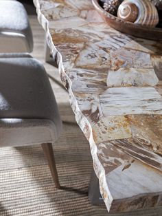 a marble table with two chairs in front of it and shells on the back wall