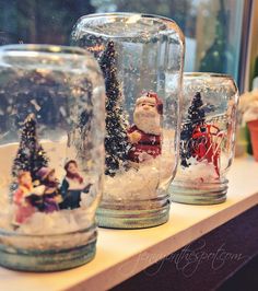 snow globes are sitting on a shelf in front of a window with christmas decorations