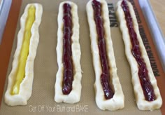 three hotdogs with ketchup and mustard on them sitting on a baking sheet