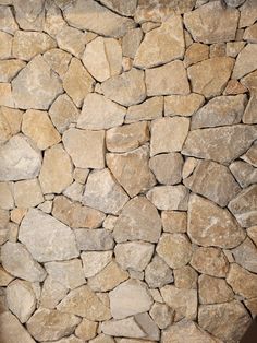 a stone wall that has been made out of various types of rocks and is brown in color