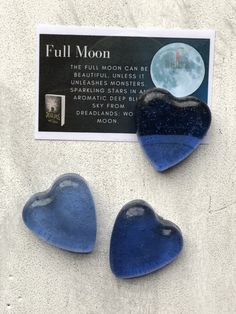 three blue heart shaped glass magnets sitting on top of a white surface next to a card