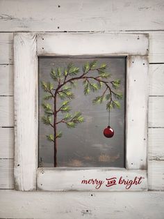 a white frame with a christmas tree and an ornament hanging from it's side