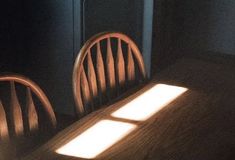 a table with two chairs and a light shining on the top one in front of it