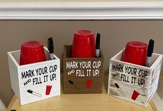 three wooden boxes with red cups in them sitting on a table next to each other