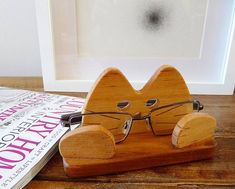 a pair of glasses sitting on top of a wooden stand in front of a magazine