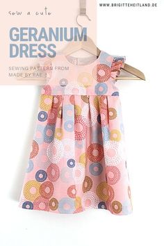 a dress hanging on a clothes hanger next to a sign that says, geranium dress sewing pattern from made by kate