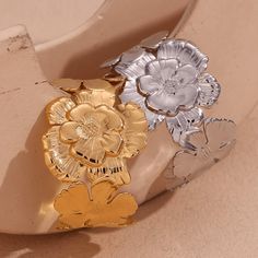 Add a touch of playfulness to your outfit with our Flower Cluster Cuff! This statement cuff bracelet features a cluster of beautiful flowers, bringing a whimsical and unique element to any look. Perfect for those who don't take themselves too seriously and like to add a bit of fun to their style. DETAILS & SIZE Finish: 18K gold plate Material: Stainless Steel Measurements: Diameter: 2.2"; Width: 1.5" Weight: 35 grams Waterproof, tarnish-resistant, and nickel free Shop Bracelets to curate your arm stack! Adjustable Flower Cuff Bracelet For Spring, Spring Wedding Metal Bracelets, Adjustable Flower Ring For Party, Spring Flower Metal Bracelets, Spring Flower-shaped Metal Bracelets, Arm Stack, Ear Bar, Statement Cuff Bracelet, Flower Cluster