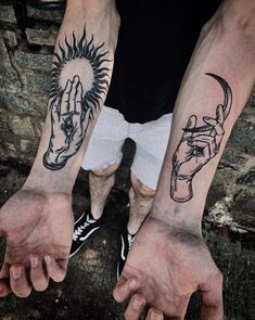 two hands holding each other with tattoos on their arms and fingers, both showing the same person's hand