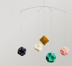 an origami mobile with three different colored geometric shapes hanging from it's sides