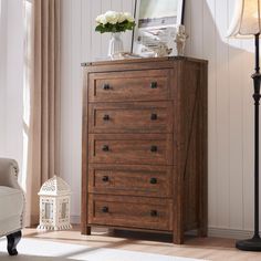 a wooden chest of drawers sitting on top of a hard wood floor next to a white chair