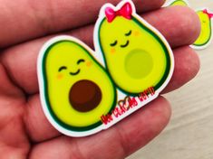 someone is holding two avocado stickers in their hand