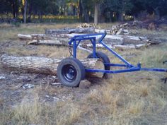 an old blue wagon is sitting in the grass next to some trees and logs with one wheel on it