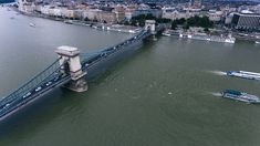 an aerial view of a bridge spanning the width of a river with boats on it