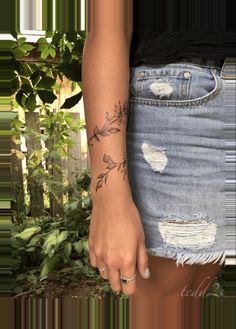 a woman with a tattoo on her left arm holding onto an old pair of jeans