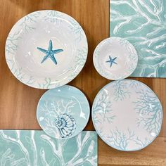 three blue and white plates with starfish designs on them sitting on a wooden table