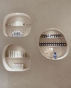 three white shelves with bottles and vases on them