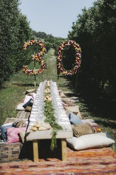 a long table with flowers on it in the middle of an apple orchard