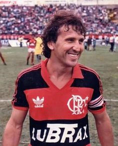 a man standing on top of a soccer field wearing a red and black uniform with white lettering