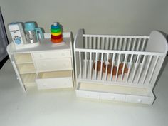 a toy crib next to a baby's bed and dresser