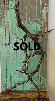 a piece of driftwood with the word sold on it in front of an old wooden door